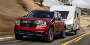 red 2024 Ford Maverick towing an rv down a country street